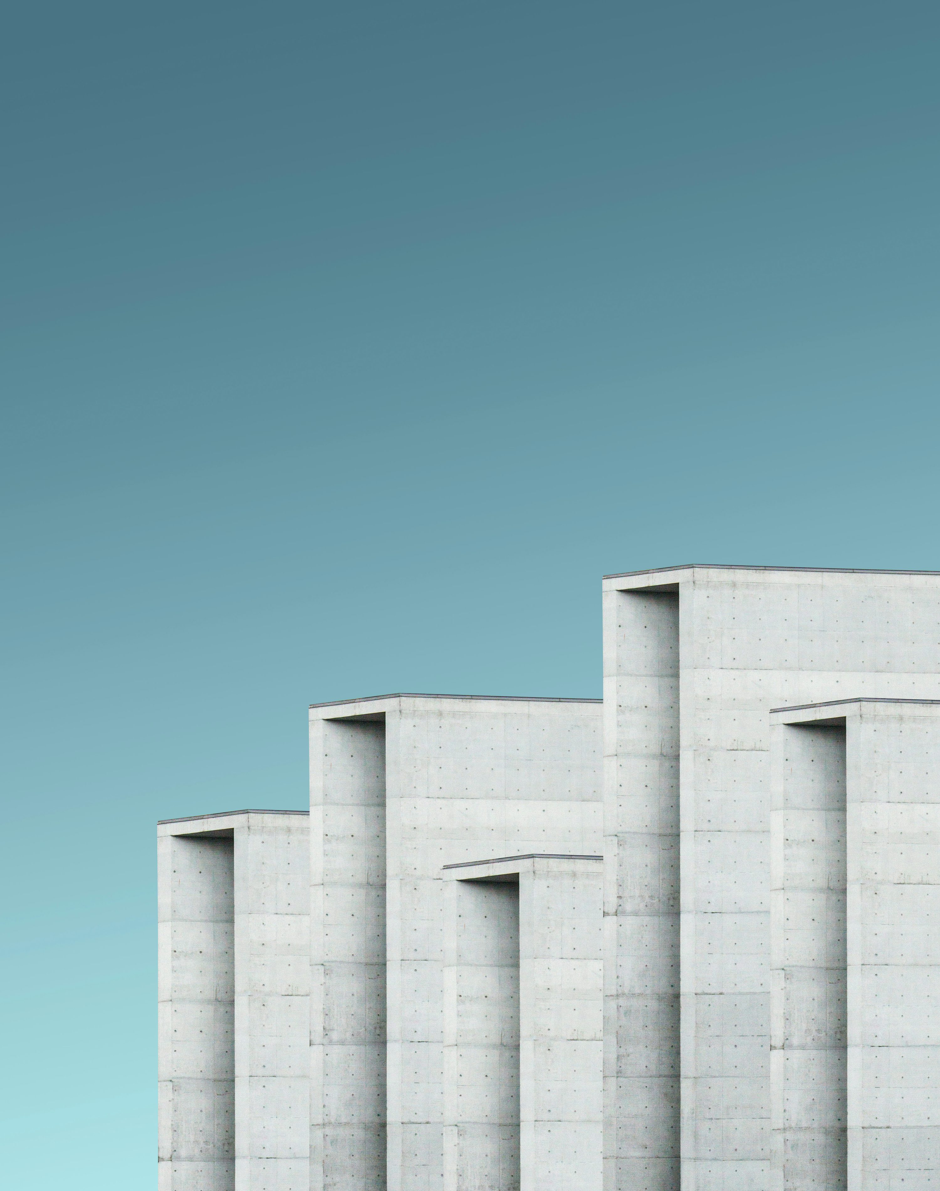 Concrete architectural pillars against a clear teal sky — symbolising structured, enduring investment